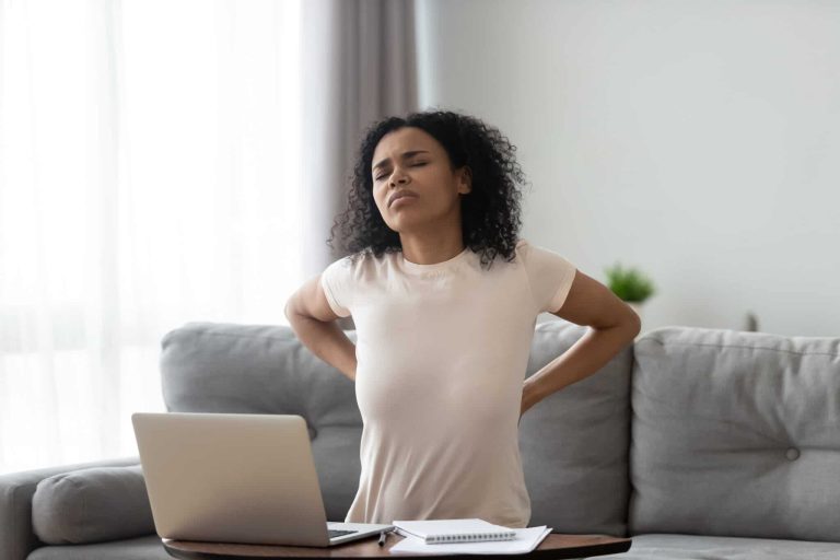 African woman feeling backpain tired of computer sit on sofa